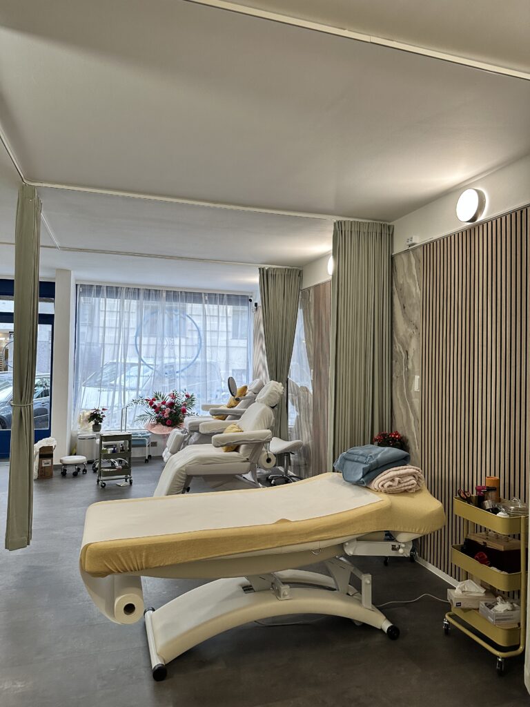 Heller Massageraum mit zwei Liegen im SanBao – Zentrum für Balance Heller Massageraum mit zwei Liegen, Tageslichtfront und Sitzbereich im SanBao – Zentrum für Balance in Wien